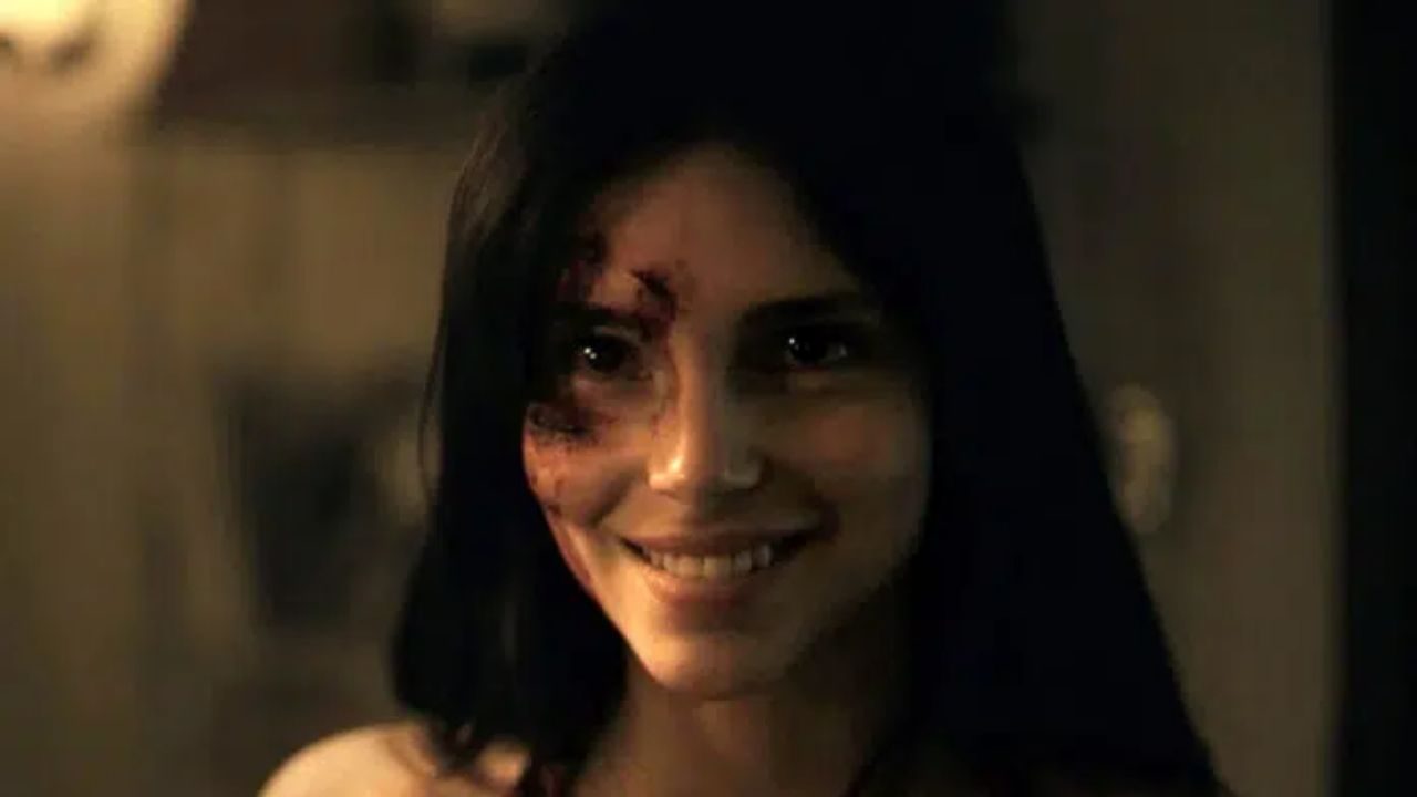 Personagem com ferimentos no rosto sorri de forma inquietante em cena da série Obsessão