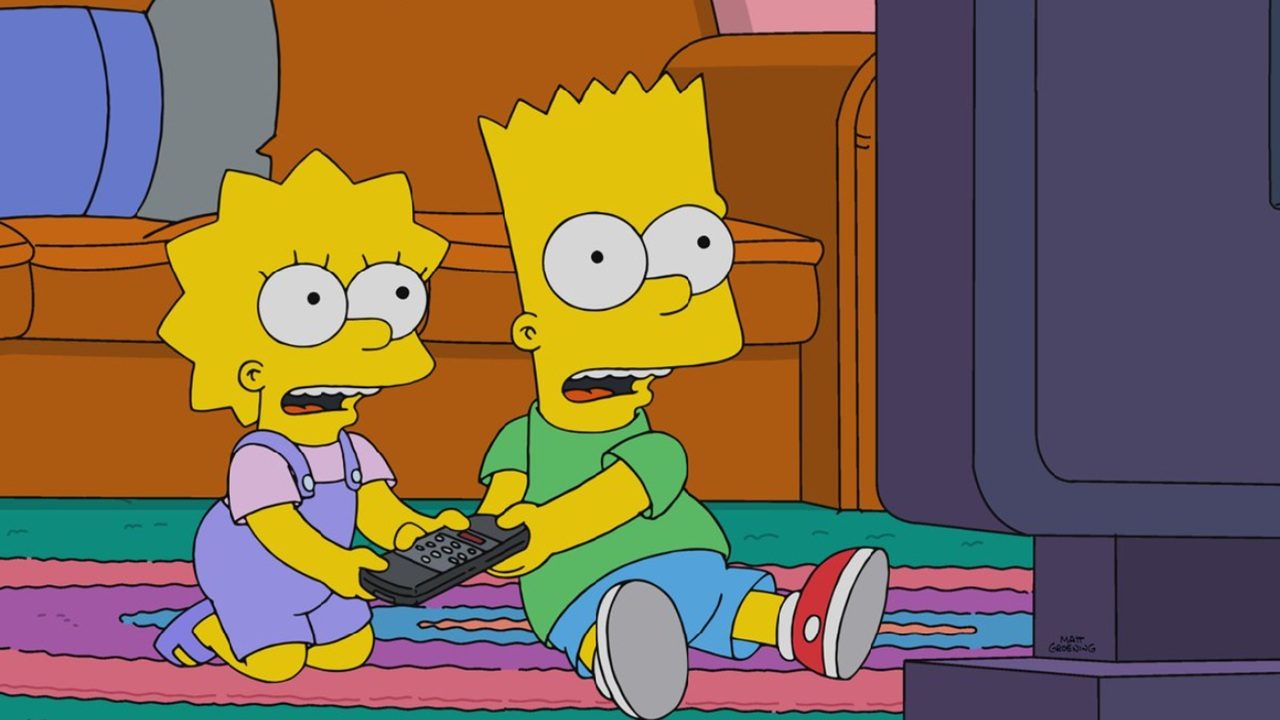 A imagem mostra Lisa e Bart Simpson, personagens animados da série The Simpsons, sentados no chão da sala assistindo TV e segurando um controle remoto
