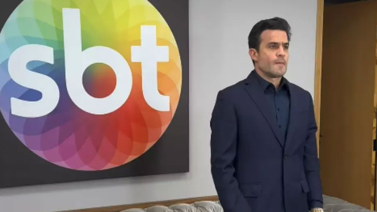 Pablo Marçal de terno escuro em frente ao logotipo do SBT em parede interna da emissora