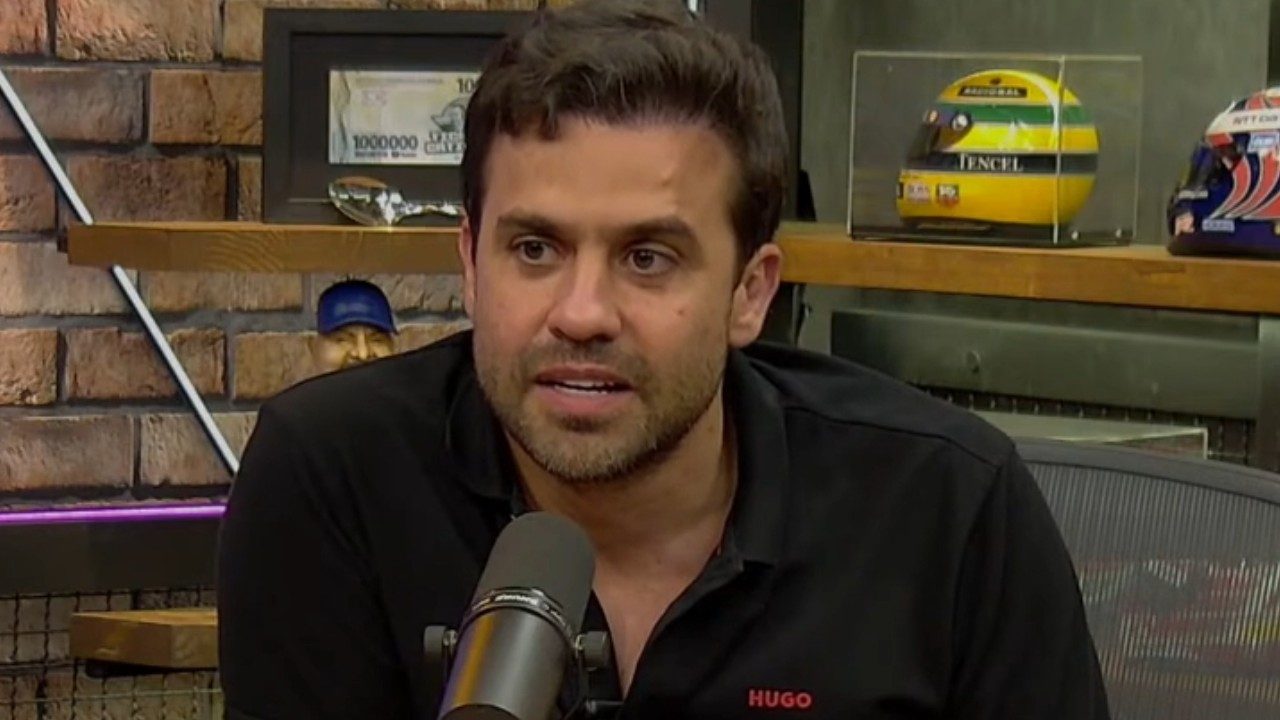 Pablo Marçal fala ao microfone durante entrevista em estúdio com prateleiras ao fundo e capacete de Ayrton Senna em exposição