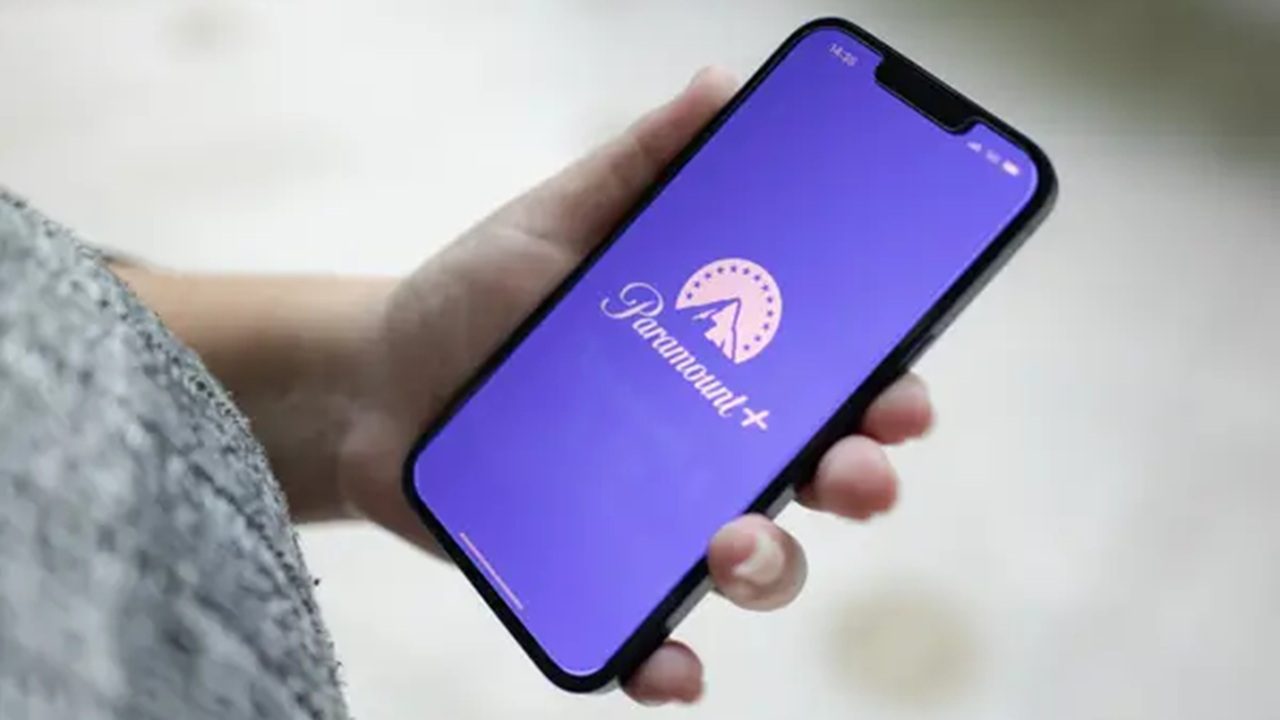 Pessoa segura um smartphone com a tela exibindo o logotipo do Paramount+ em fundo roxo, indicando acesso ao aplicativo de streaming.