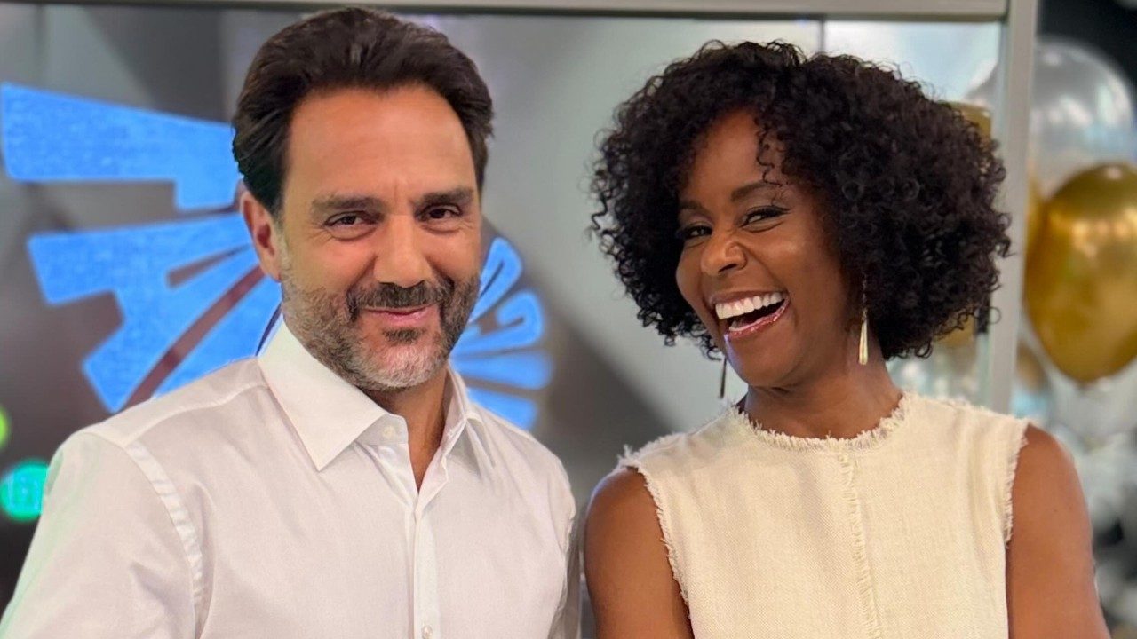 Paulo Renato Soares e Maju Coutinho sorriem lado a lado em estúdio do Fantástico com painel iluminado ao fundo