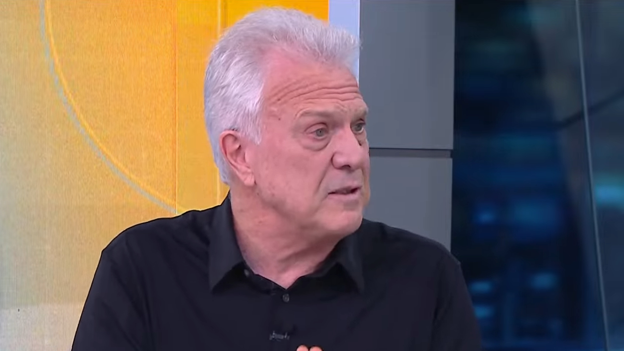 Pedro Bial fala durante participação em programa de TV com cenário colorido ao fundo