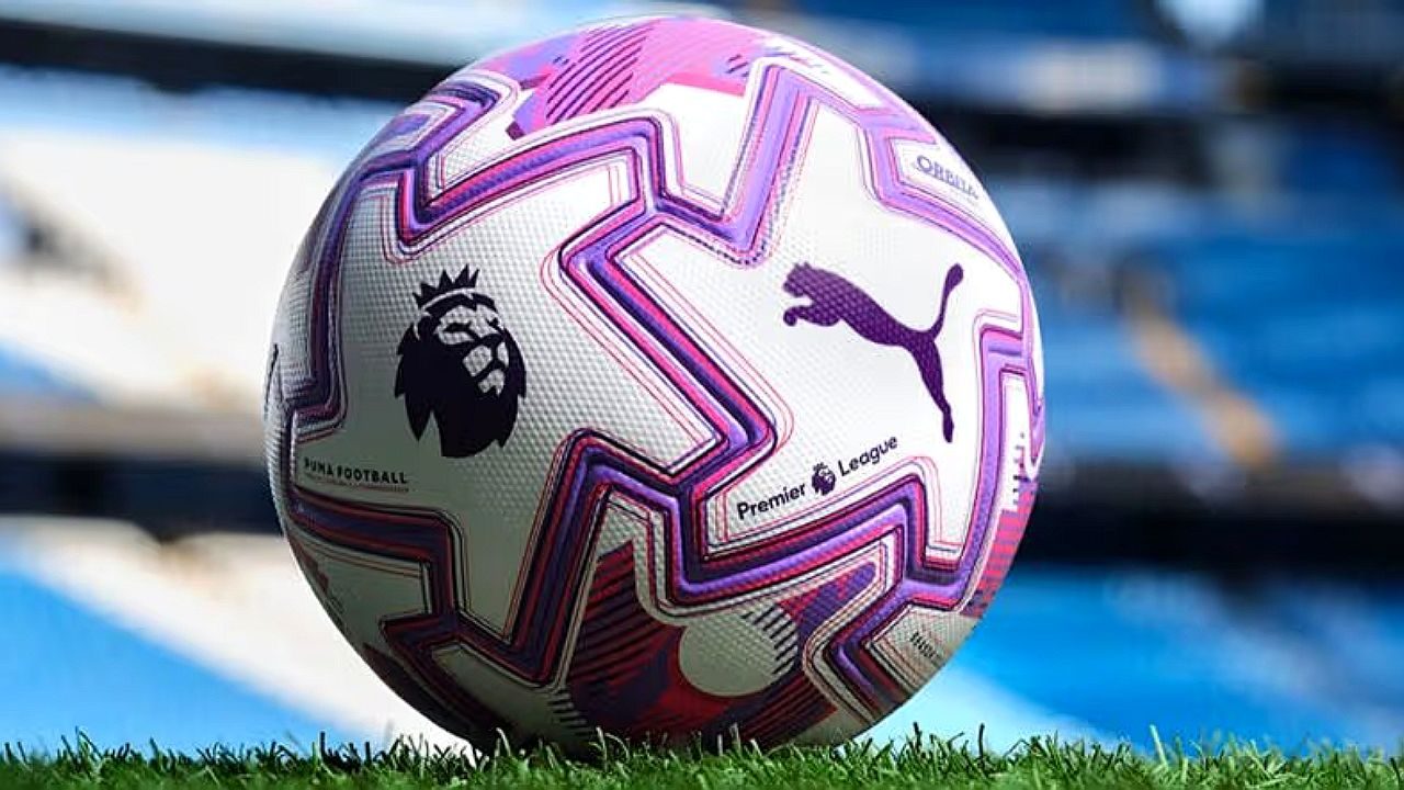 Bola oficial da Premier League com logotipos da competição e da Puma sobre gramado de estádio de futebol