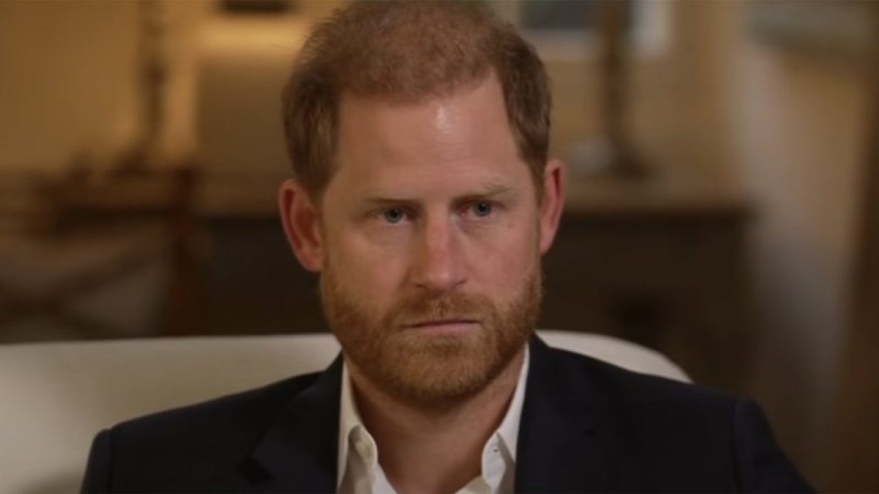 Príncipe Harry com expressão séria durante entrevista em ambiente interno com iluminação suave