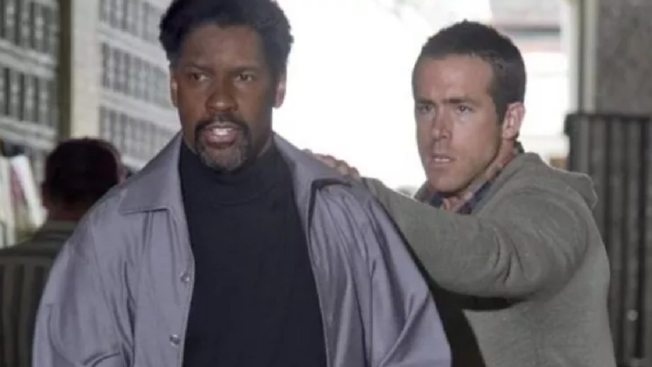 Dois homens caminham lado a lado em ambiente urbano fechado, com expressão tensa; um deles apoia a mão no ombro do outro, sugerindo situação de urgência ou confronto.