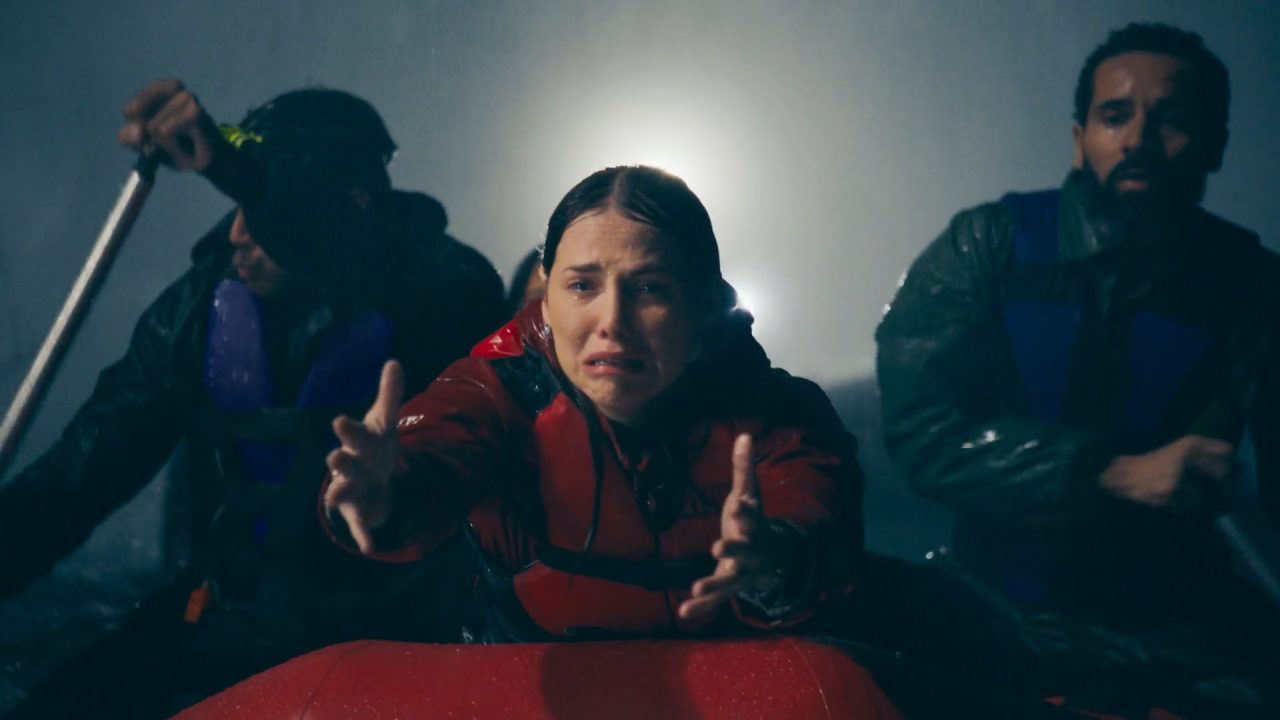 Adriana, interpretada por Letícia Colin, chora e estende os braços durante resgate em bote inflável sob forte chuva em cena de Quem Ama Cuida, novela da Globo.