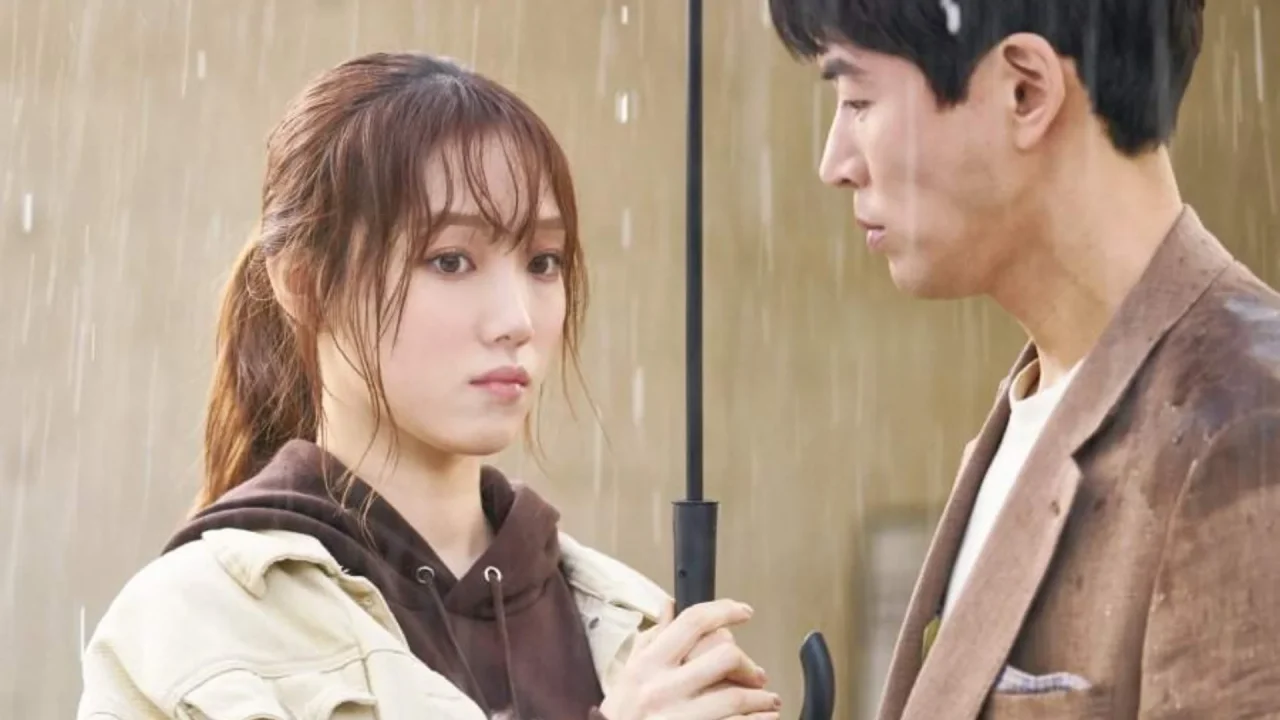 Personagens da série Questão de Tempo dividem guarda-chuva em cena sob a chuva