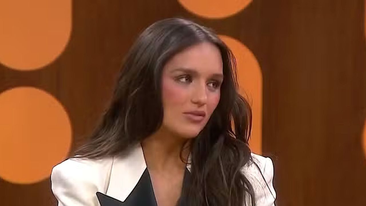 Rafa Kalimann participa de entrevista em programa de TV com blazer branco e fundo laranja