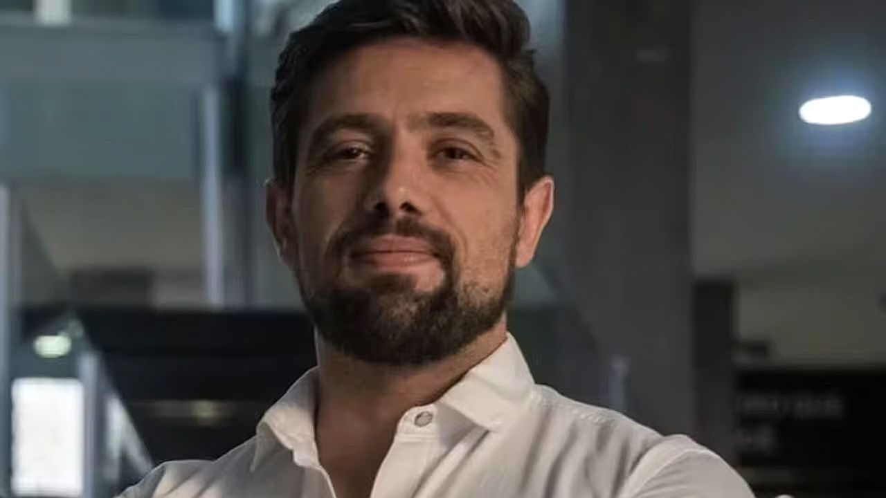 Rafael Cardoso de camisa branca posa em ambiente corporativo em foto de divulgação do ator