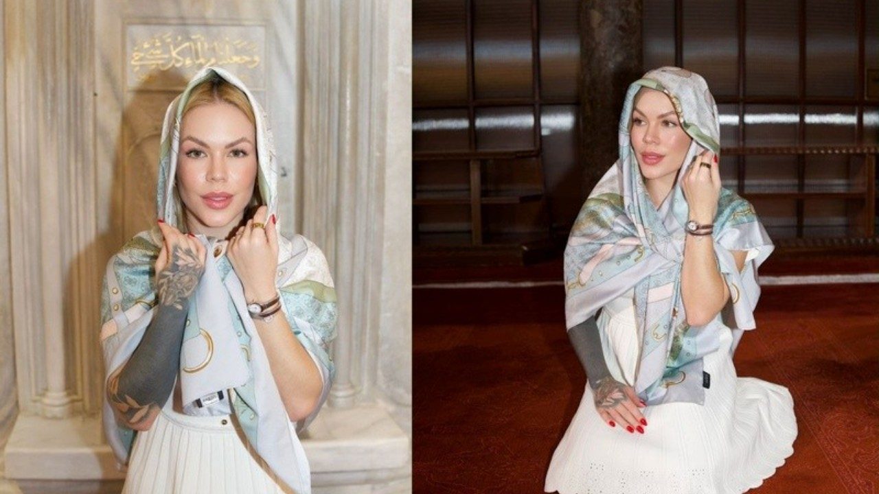 Ravena Hanniely com lenço sobre a cabeça e vestido branco posa em ambiente religioso com colunas e salão ao fundo