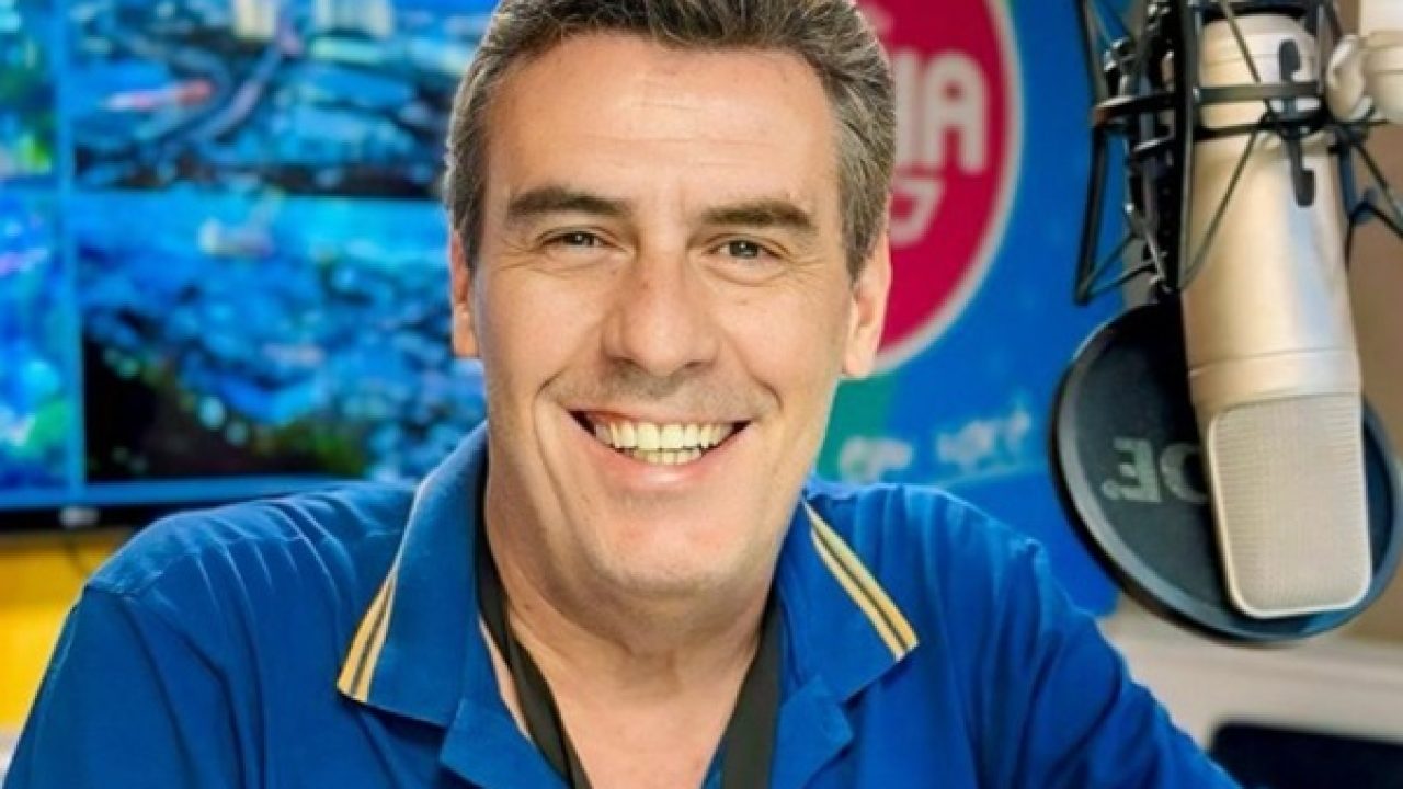 Emmerson José sorrindo na frente do microfone em estúdio de rádio