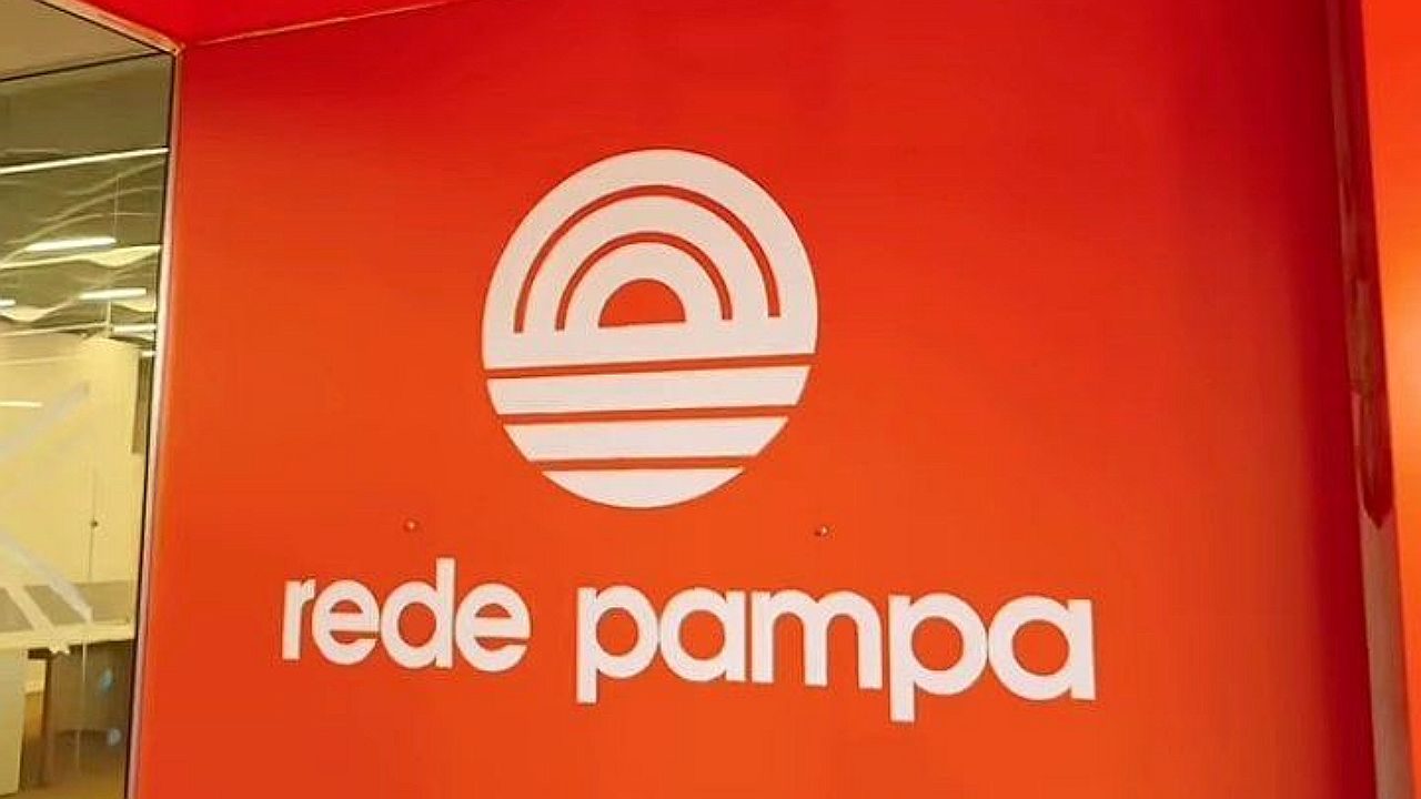 Logotipo da Rede Pampa exibido em parede vermelha dentro da sede da emissora