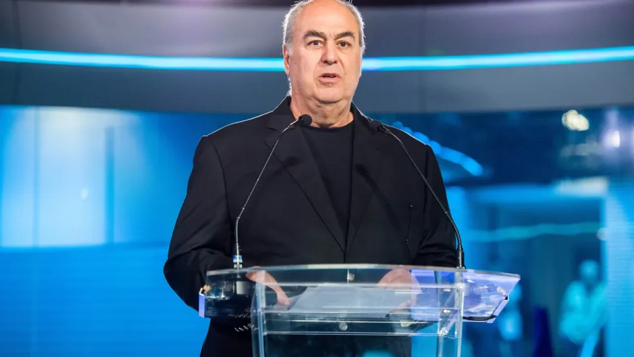 Roberto Irineu Marinho em púlpito durante evento da Globo, com microfones e iluminação azul ao fundo