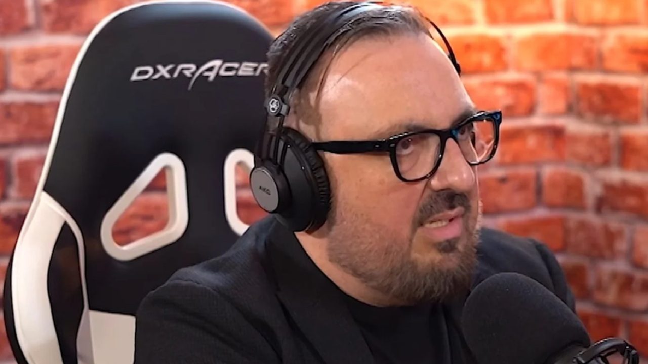 Homem usa fones de ouvido e fala em microfone durante gravação de podcast, sentado em cadeira preta diante de parede de tijolos aparentes