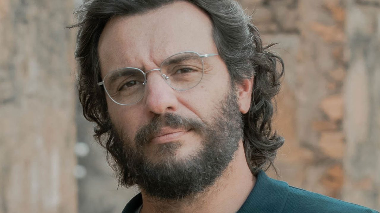 Rodrigo Lombardi caracterizado como o cientista Otto com barba, óculos e expressão séria na série Vermelho Sangue