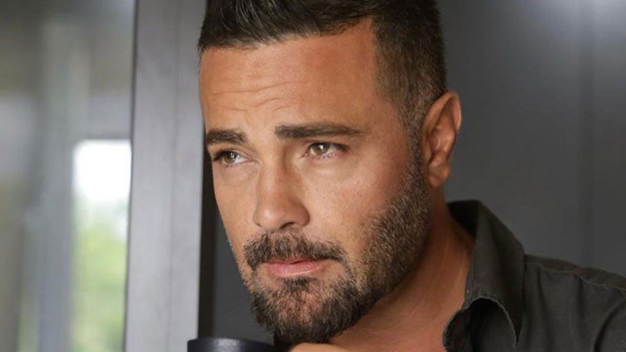 Rodrigo Phavanello com barba aparada e camisa cinza escura olha para o lado com expressão pensativa em close-focado sob iluminação suave natural