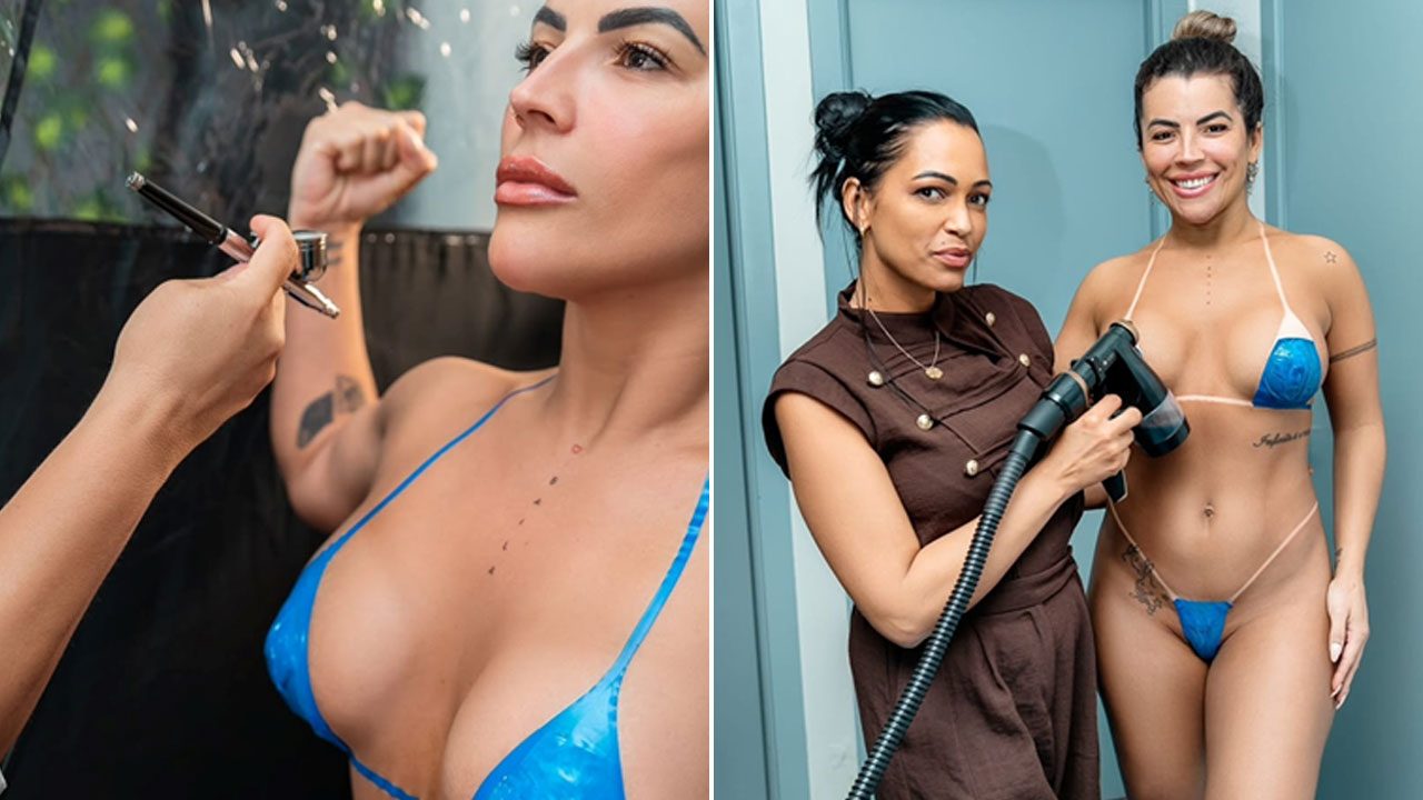 Rosana Ferreira de biquíni azul recebe bronzeamento artificial e posa ao lado da profissional em ambiente interno