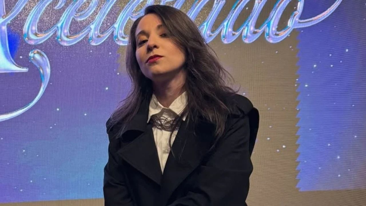 Yrla Braga caracterizada como Rosinha posa diante do painel de Coração Acelerado em foto de divulgação da novela