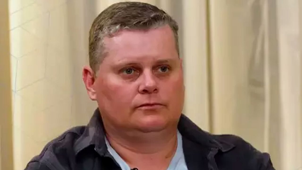 Texto Alternativo disse: Homem com expressão séria participa de entrevista em programa de televisão com cenário interno claro ao fundo