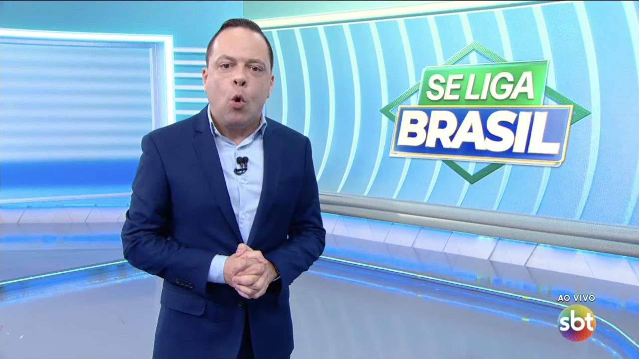 Thiago Gardinali apresenta o Se Liga, Brasil no estúdio do SBT diante do logotipo do programa.