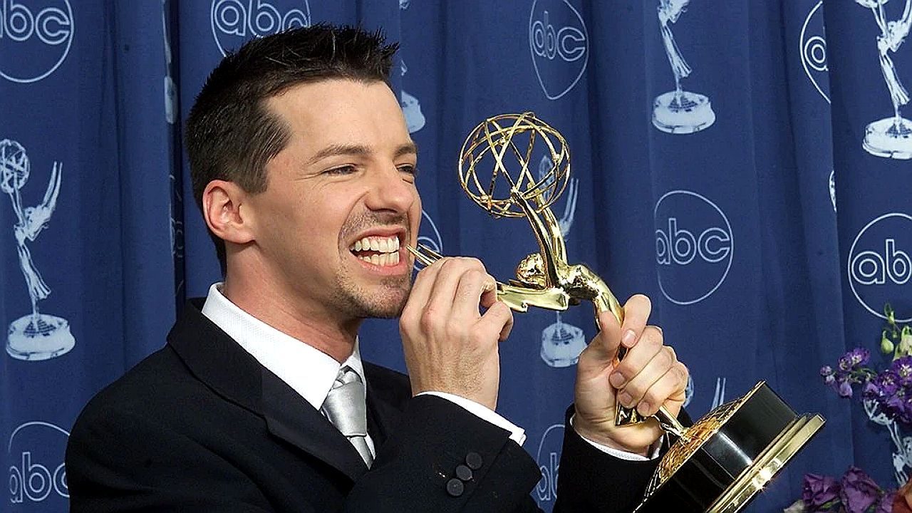 Homem morde estatueta do Emmy enquanto posa para fotos em premiação com logotipo da ABC ao fundo