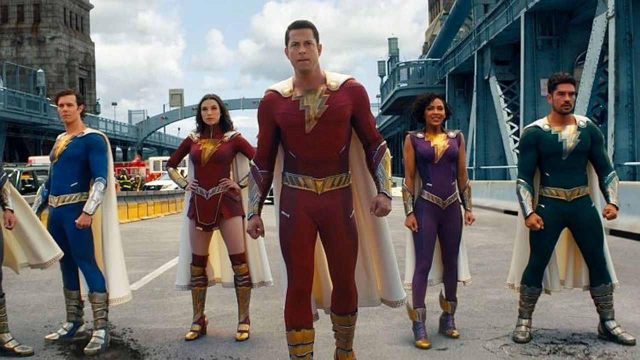 Shazam e equipe de heróis posam com uniformes coloridos em rua após ação em cena de filme