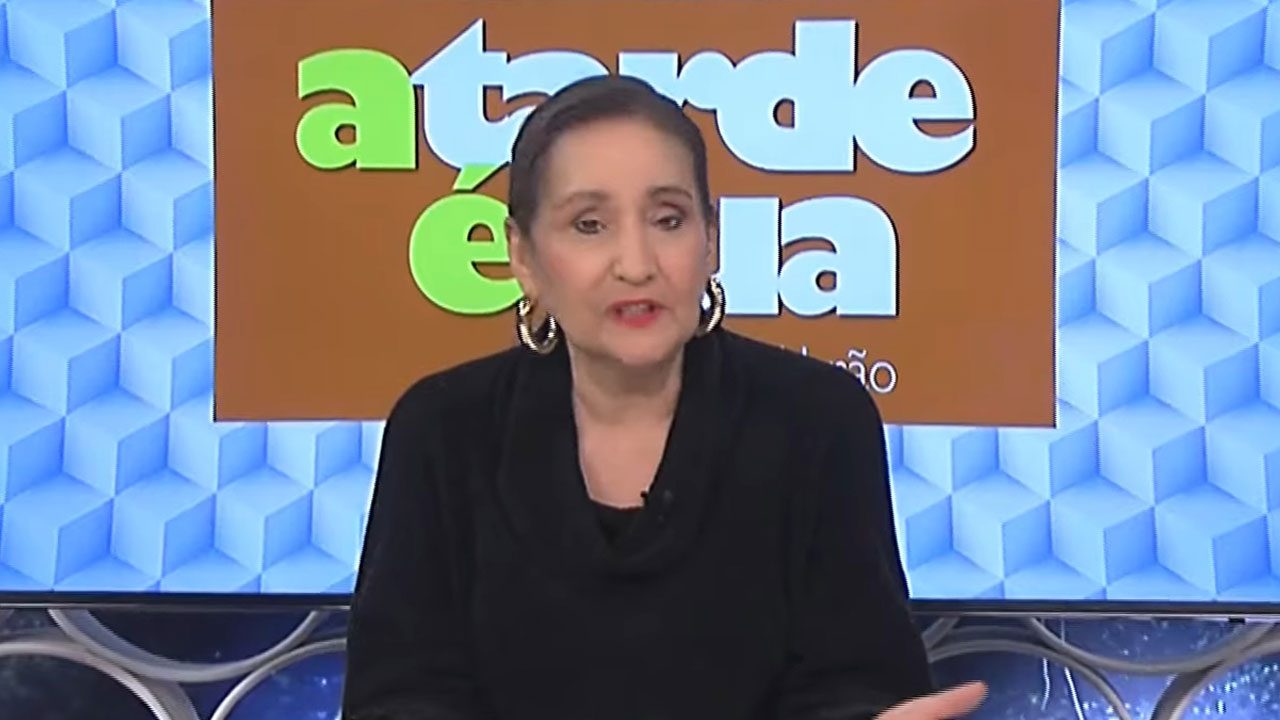 Apresentadora Sonia Abrão sentada à bancada do programa A Tarde É Sua, da RedeTV!, durante apresentação da atração