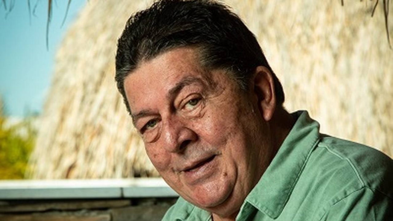 Stepan Nercessian com uma camisa verde no fundo de palha