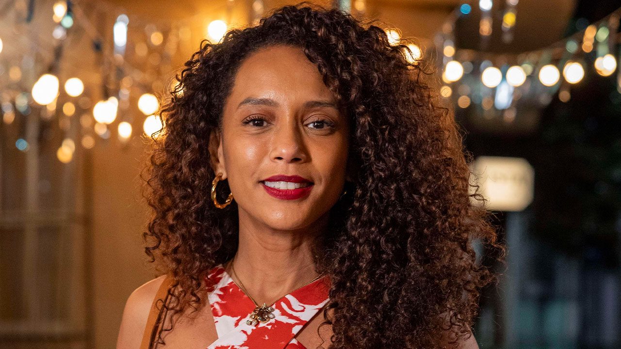 Taís Araujo caracterizada como Raquel com vestido estampado e cabelo solto em foto promocional da novela Vale Tudo