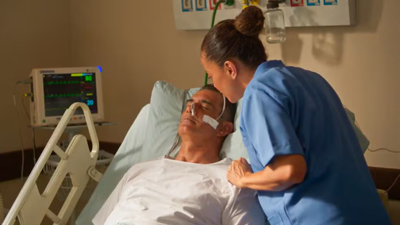 Homem acamado com uma mulher vestida de enfermeira ao lado