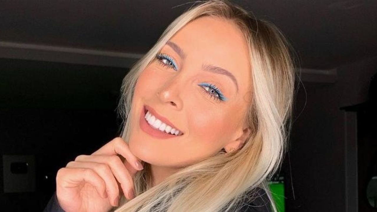 Tata Estaniecki sorrindo com maquiagem em tons de azul e cabelo loiro solto