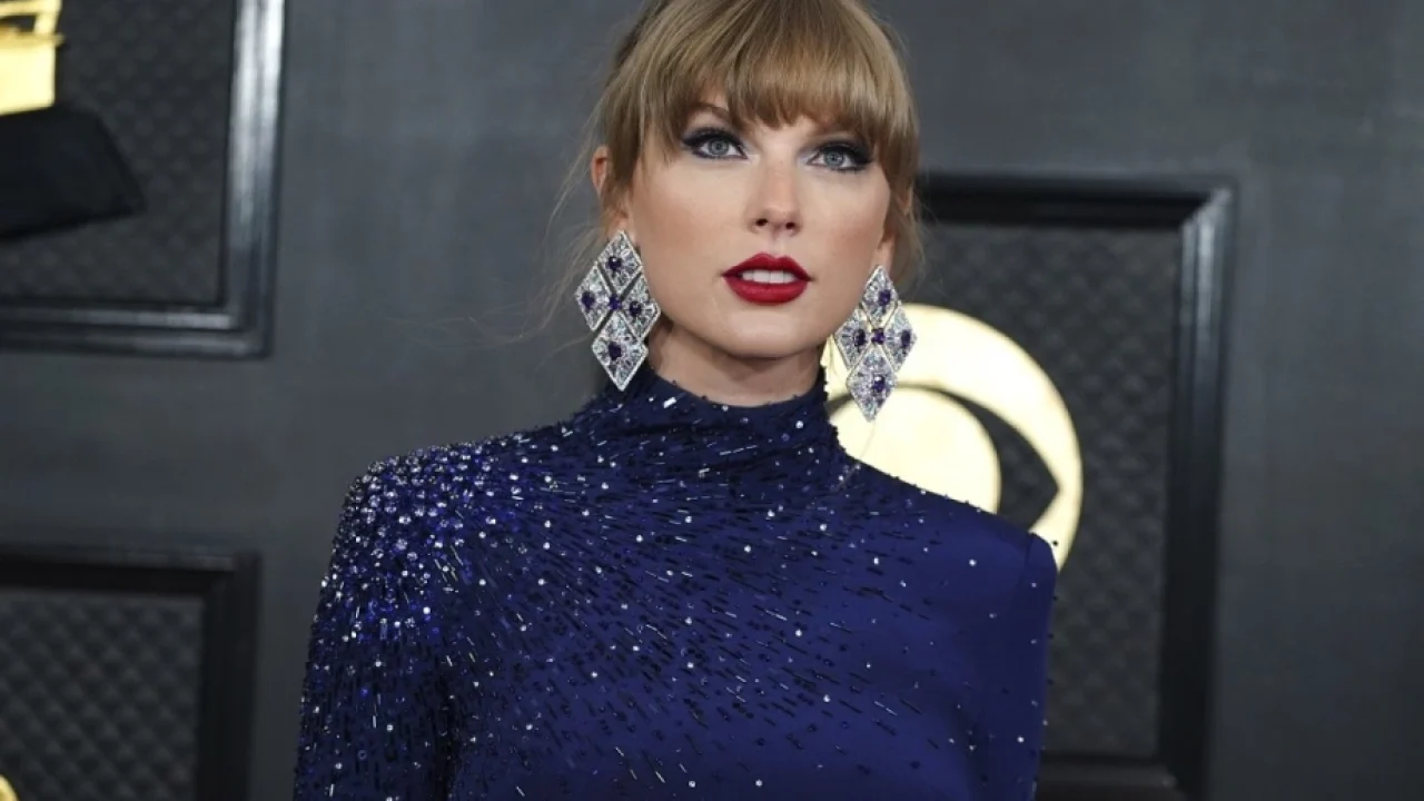 Taylor Swift usa vestido azul brilhante e brincos grandes no tapete vermelho do Grammy