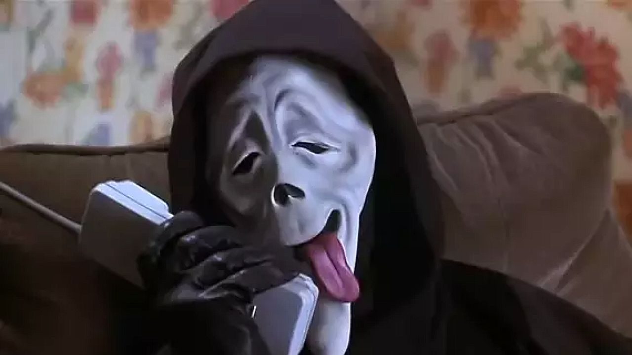 Ghostface segura um telefone com máscara de expressão exagerada em cena do filme Todo Mundo em Pânico