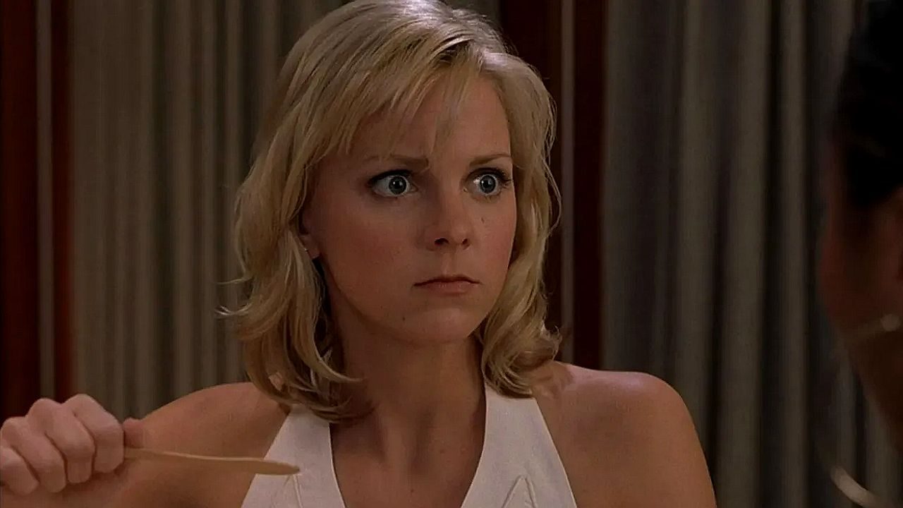 Mulher loira com expressão surpresa segura hashis durante refeição em cena de série ou filme