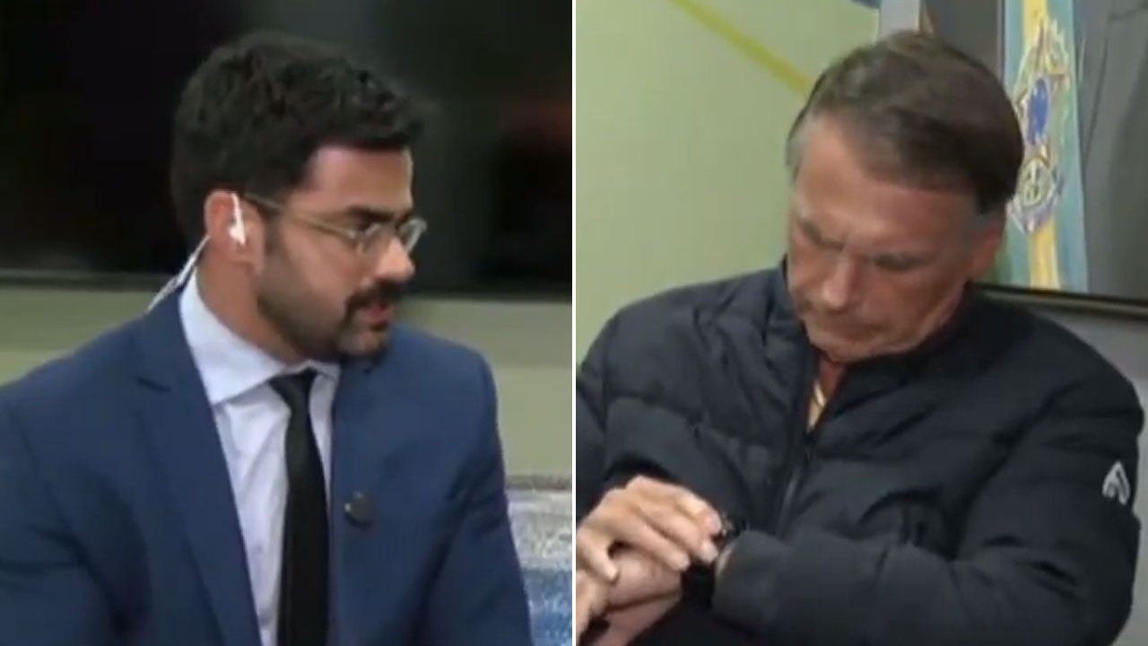 Túlio Amâncio entrevista Jair Bolsonaro que olha para o relógio durante transmissão na BandNews