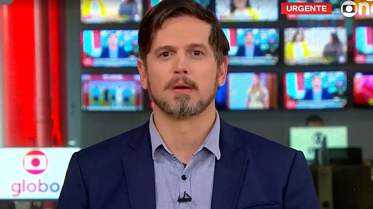 Vinícius Leal apresenta plantão de notícias da GloboNews em frente ao telão da redação da emissora