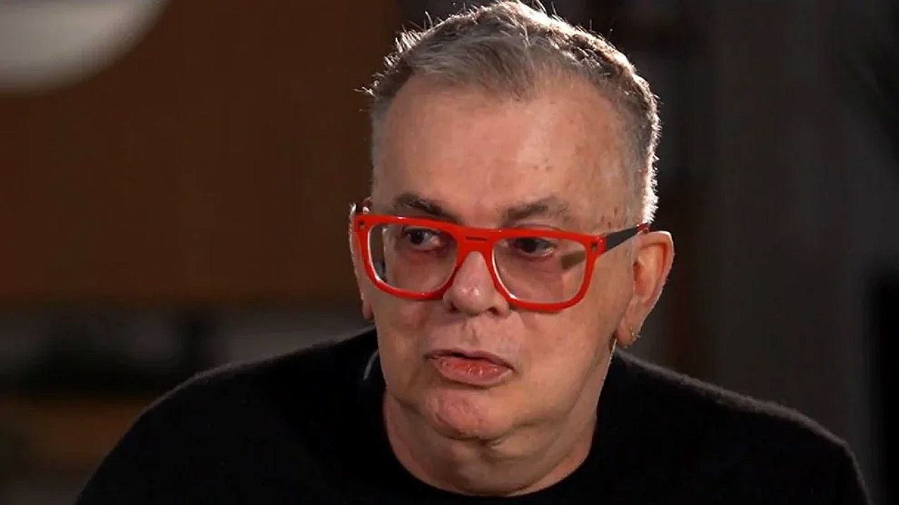 Walcyr Carrasco usa óculos vermelhos durante entrevista em programa de TV sobre música e cultura