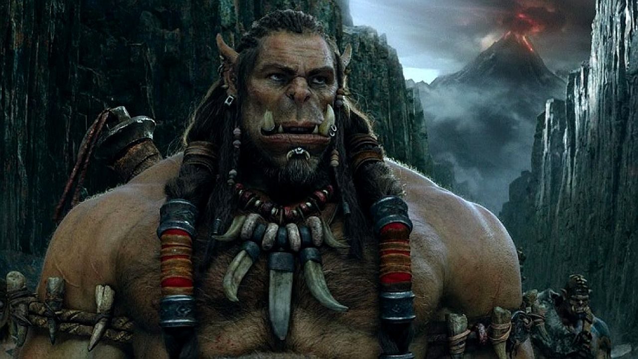 Personagem orc com presas e armadura aparece em cenário sombrio de fantasia com vulcão ao fundo