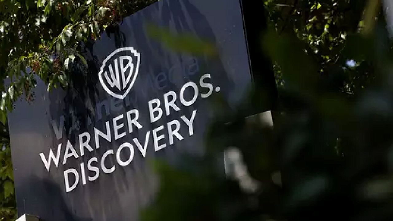 Logotipo da Warner Bros. Discovery exibido em placa externa cercada por árvores e folhagem